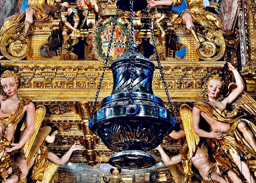 Close-up of a gold and ornate altar featuring angels and a central hanging incense burner.