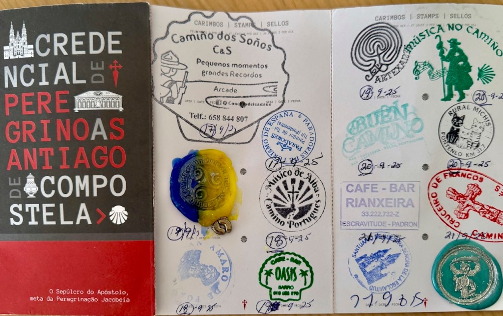 A pilgrim's credential pamphlet featuring various stamps from locations along the Camino de Santiago, with the title 'Credencial de Peregrinos Santiago de Compostela' displayed prominently.
