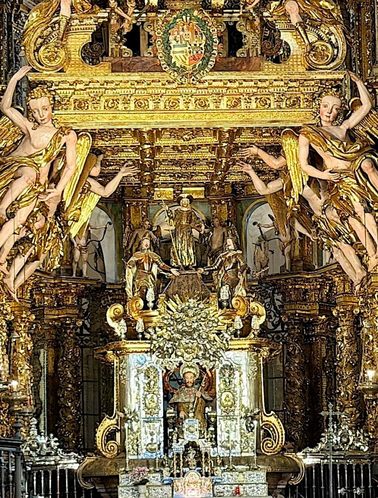 A richly decorated altar with intricate golden carvings, featuring angelic figures and ornate statues, in a historic church interior.